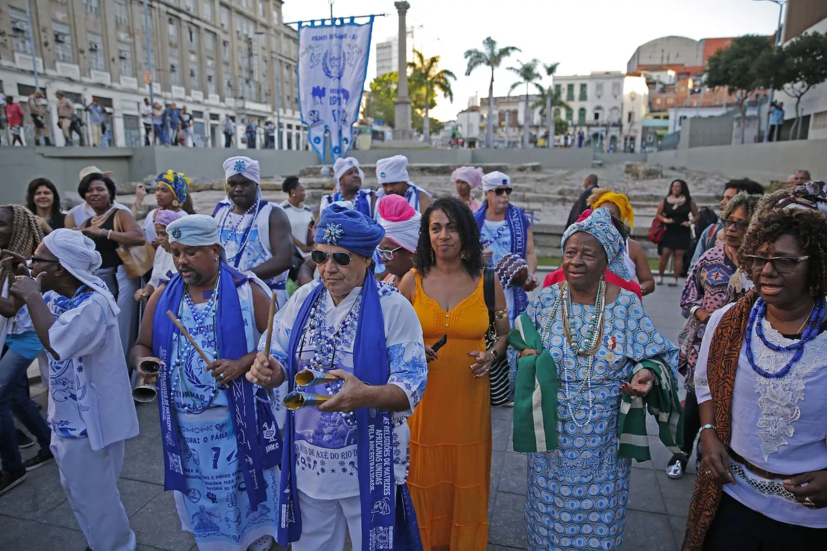Members of an afoxé group in blue and white costumes and turbans singing at the Valongo Wharf site